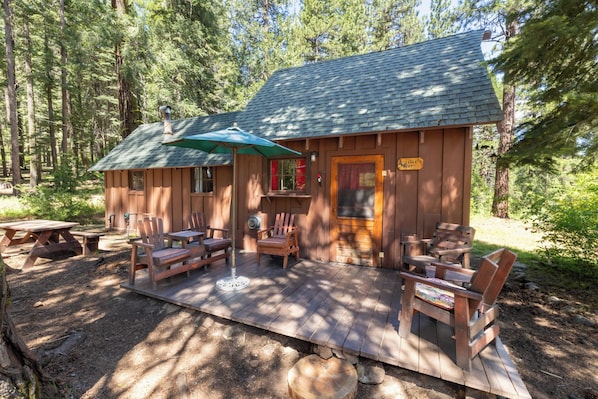 A wooden cabin with a porch, outdoor seating, and a sign reading 'Eagle's Nest.'