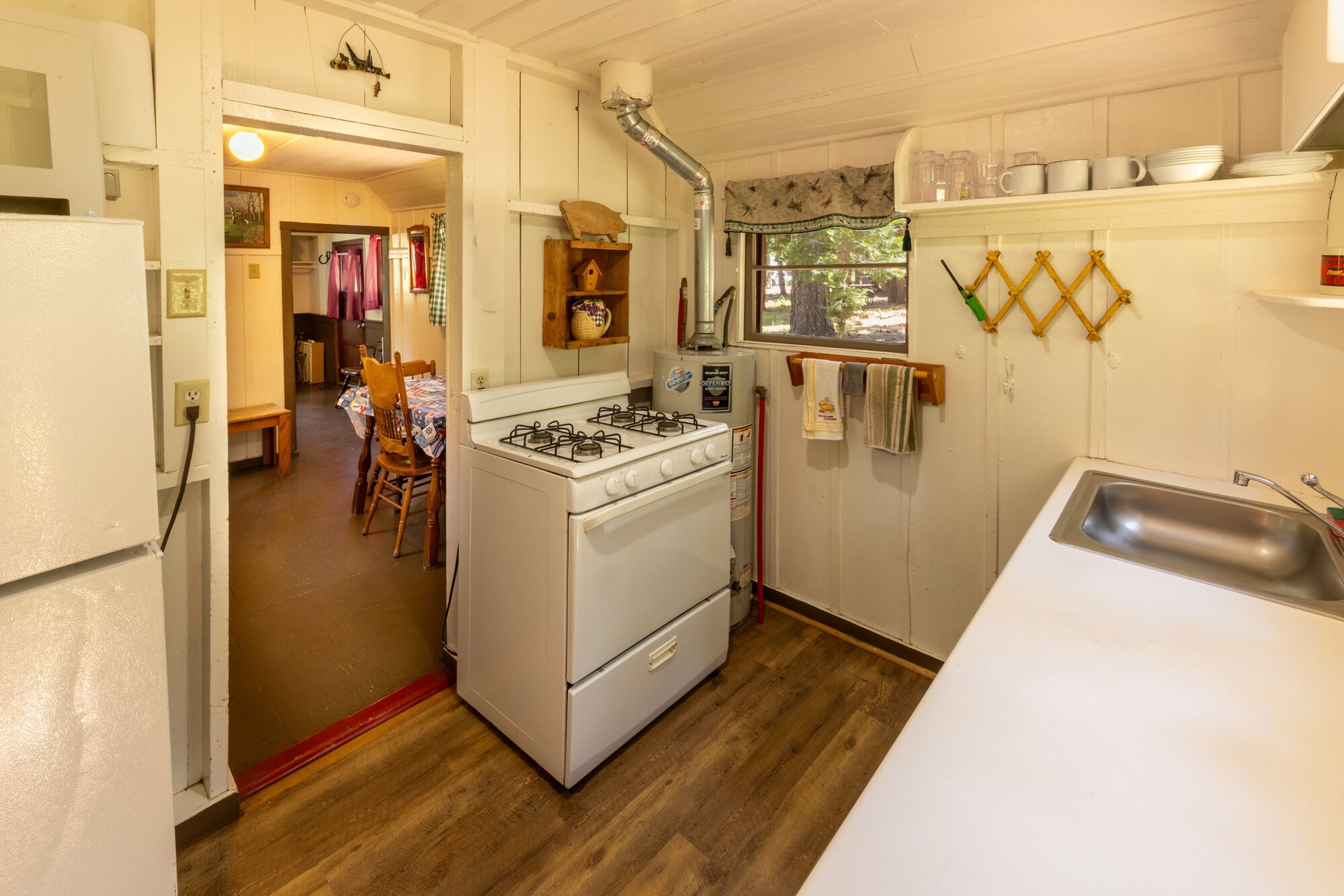 Une cuisine compacte équipée d’une cuisinière, d’un four et d’un évier. Un coin repas avec une table et des chaises est également prévu.