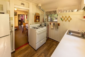 A compact kitchen with a stove, oven, and sink. There is a dining area with a table and chairs.