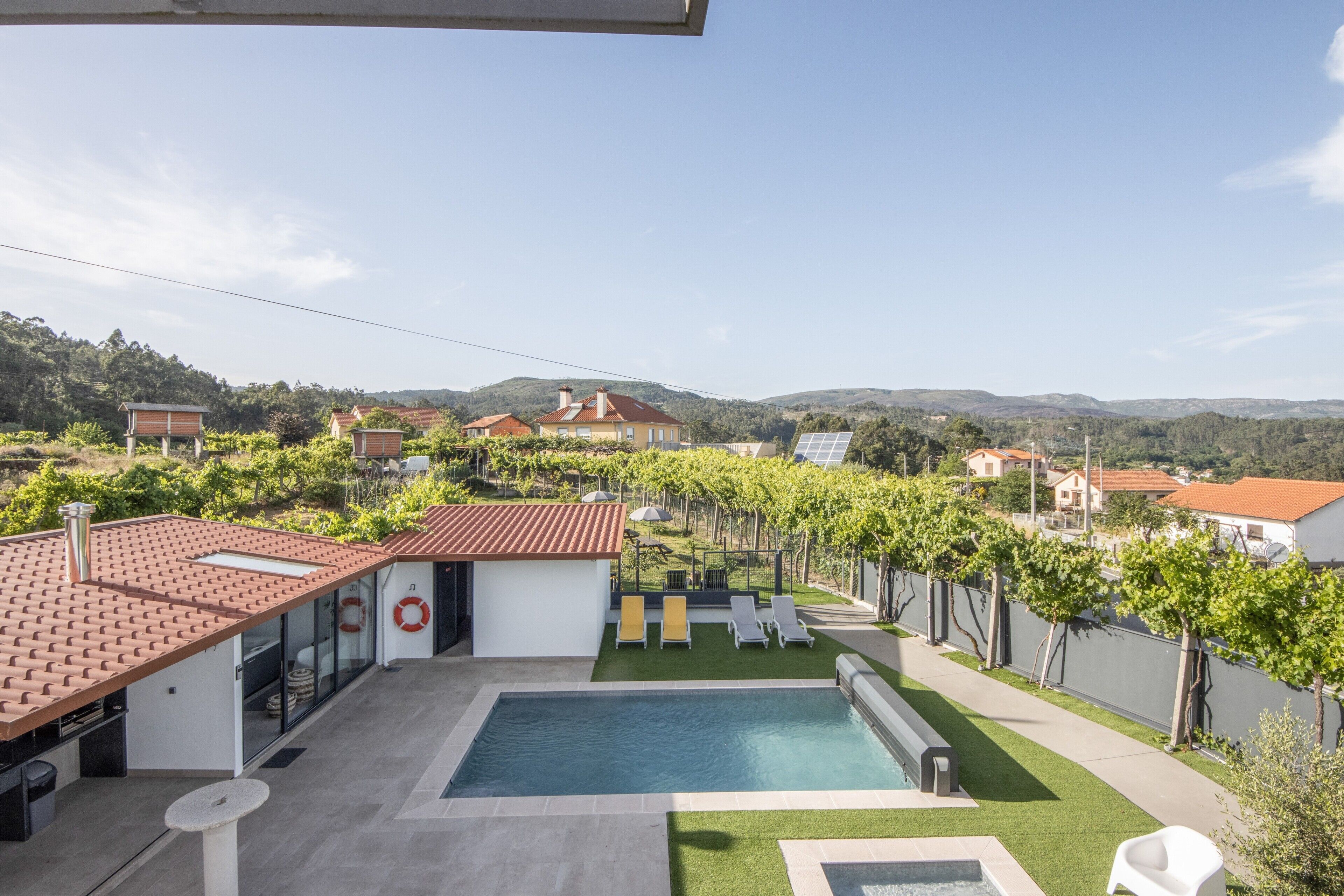 A swimming pool with a view of vineyards and houses.