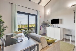 Ein modernes Wohnzimmer mit einer Couch, einem Esstisch, einem Fernseher und einem Balkon mit Blick.