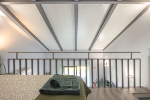 Ein Hotelzimmer mit Bett, einem fenster mit Vorhängen, Blickrichtung nach draußen und einem Balkongeländer.
