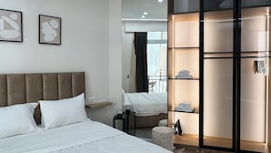 Una habitación de hotel moderna con una cama grande, un armario con puertas correderas y vistas al balcón.