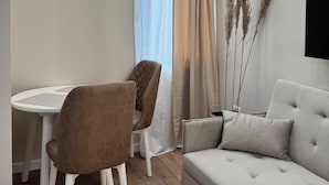 Una sala de estar moderna con un sofá, dos sillones, una mesita, un aire acondicionado y una ventana con cortinas.
