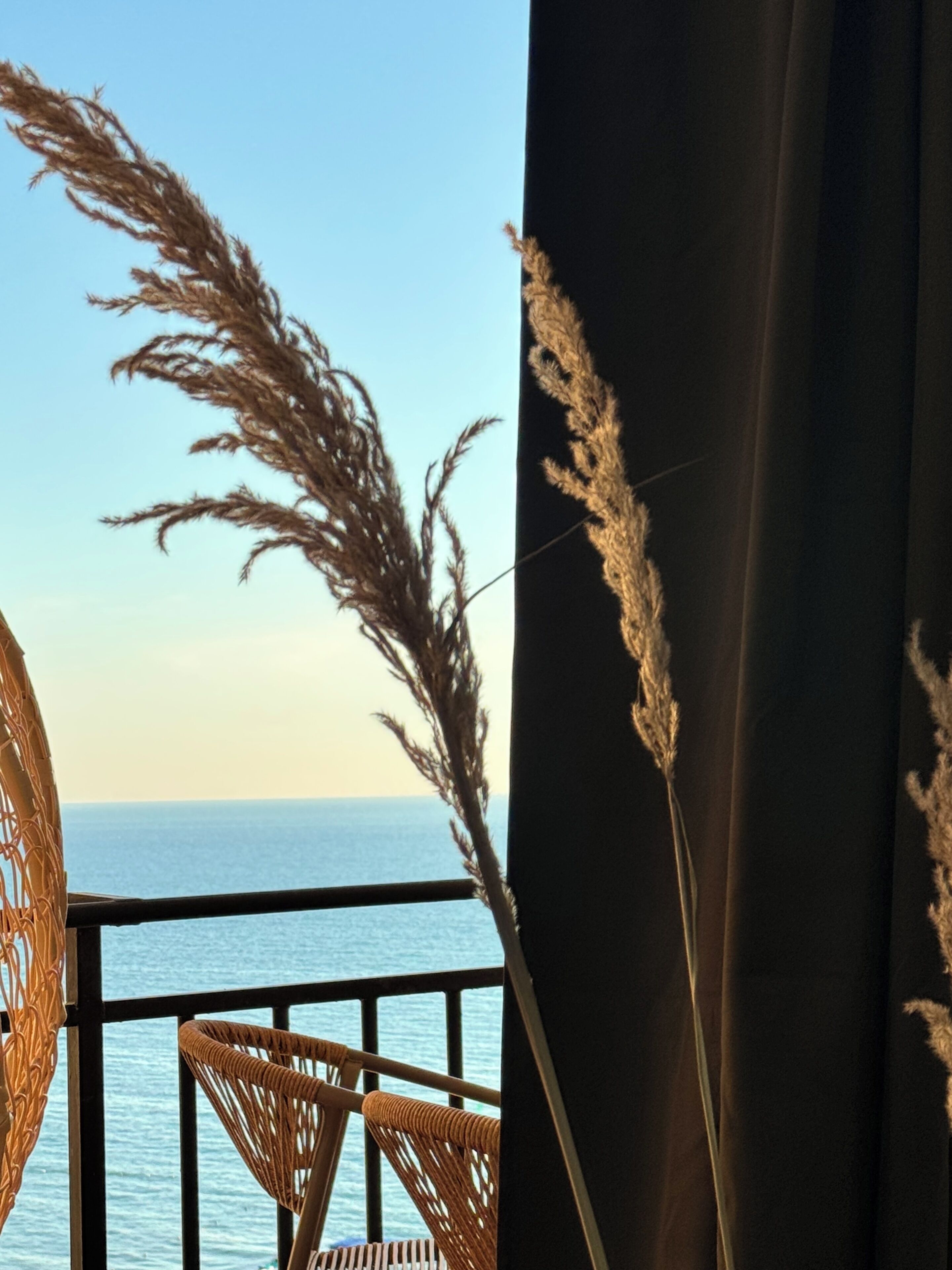 Un balcón con sillas de mimbre y vista al mar.