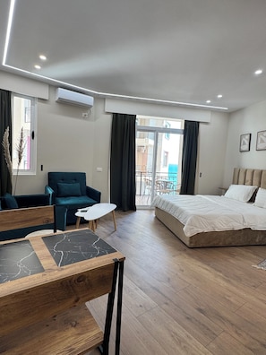 Habitación de hotel moderna con cama, sofá, una mesita y balcón con vistas.
