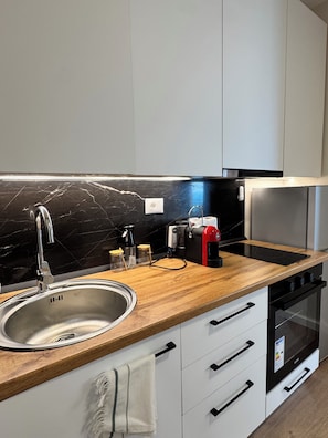 Una cocina moderna con un lavamanos de acero inoxidable, encimera de madera y armarios blancos.