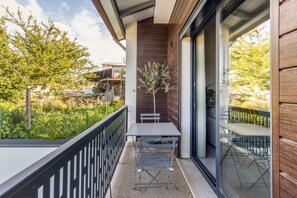 Ein Balkon mit Tisch und Stühlen, ein kleiner Baum und Blick ins grüne Umland.