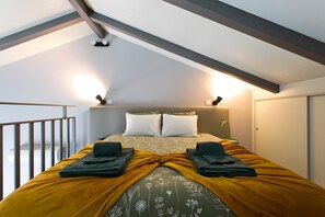 Ein Schlafzimmer mit einem Bett, zwei Nachttischlampen, einem Fenster und einem Balkon.