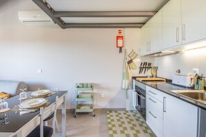 Eine moderne Küche mit Essbereich, darunter ein Tisch für zwei Personen, eine Kücheninsel und ein eingebauter Backofen.