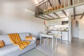 Ein modernes Apartment mit Wohnzimmer, Essbereich, einer Küchenzeile und einem Schlafzimmer auf dem Dachboden.