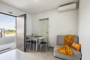 Ein modernes Zimmer mit Esstisch, Stühlen, einer Couch und einer Klimaanlage.