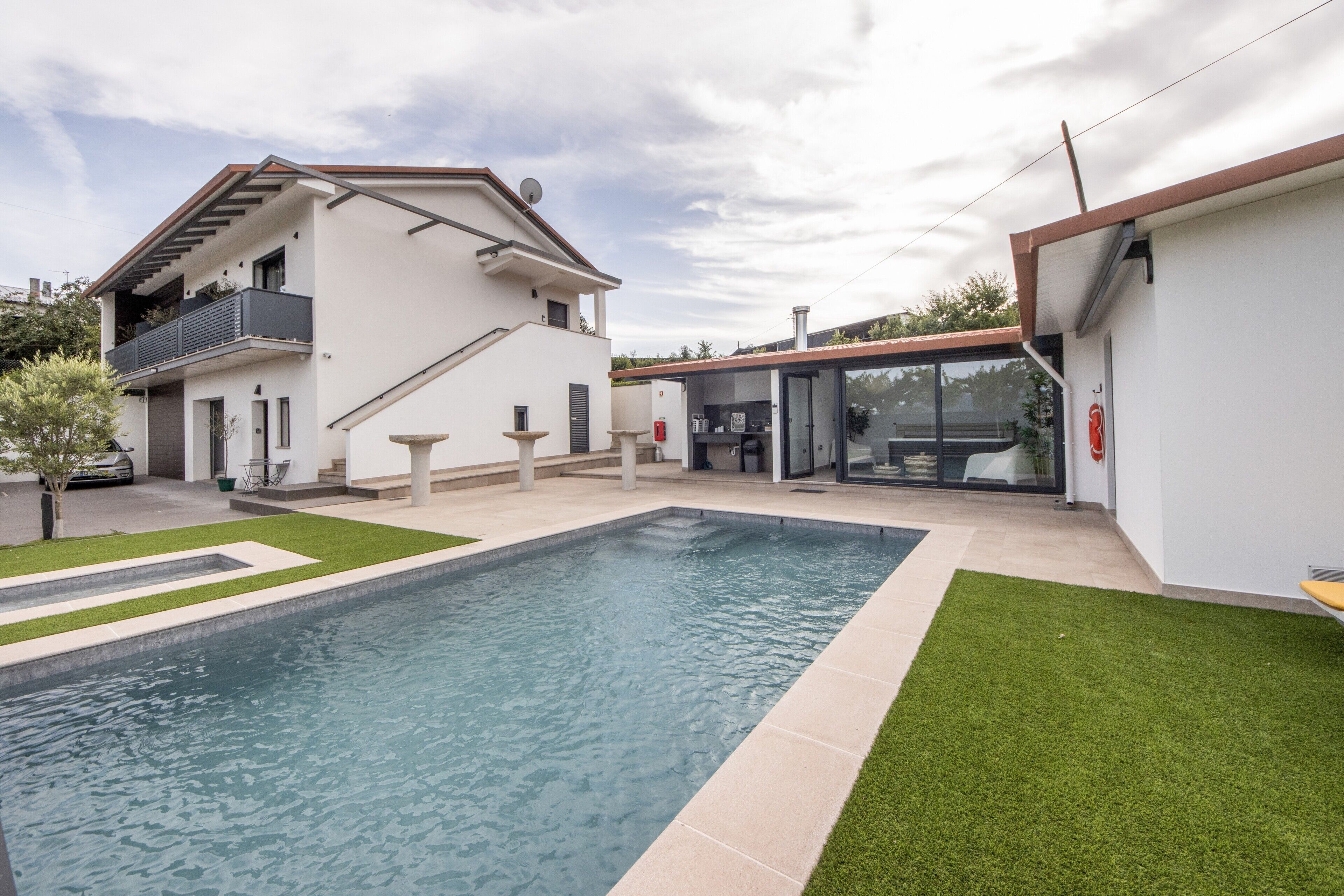 A modern house with a swimming pool, a balcony, and a patio area.