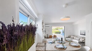 Ein moderner Essbereich mit Tisch für vier Personen, einer Couch und Blick ins Freie.