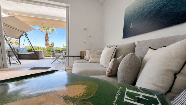 Ein modernes Wohnzimmer mit Billardtisch, einer Couch mit Kissen und einem Gemälde eines Segelboots an der Wand.