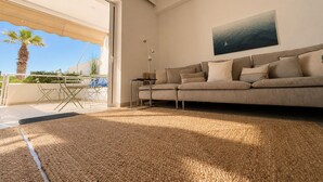 Ein modernes Wohnzimmer mit einer Couch, einem Gemälde und Blick ins Freie.