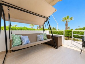Un espacio al aire libre techado con asientos colgantes, cojines estampados y una cesta de mimbre.