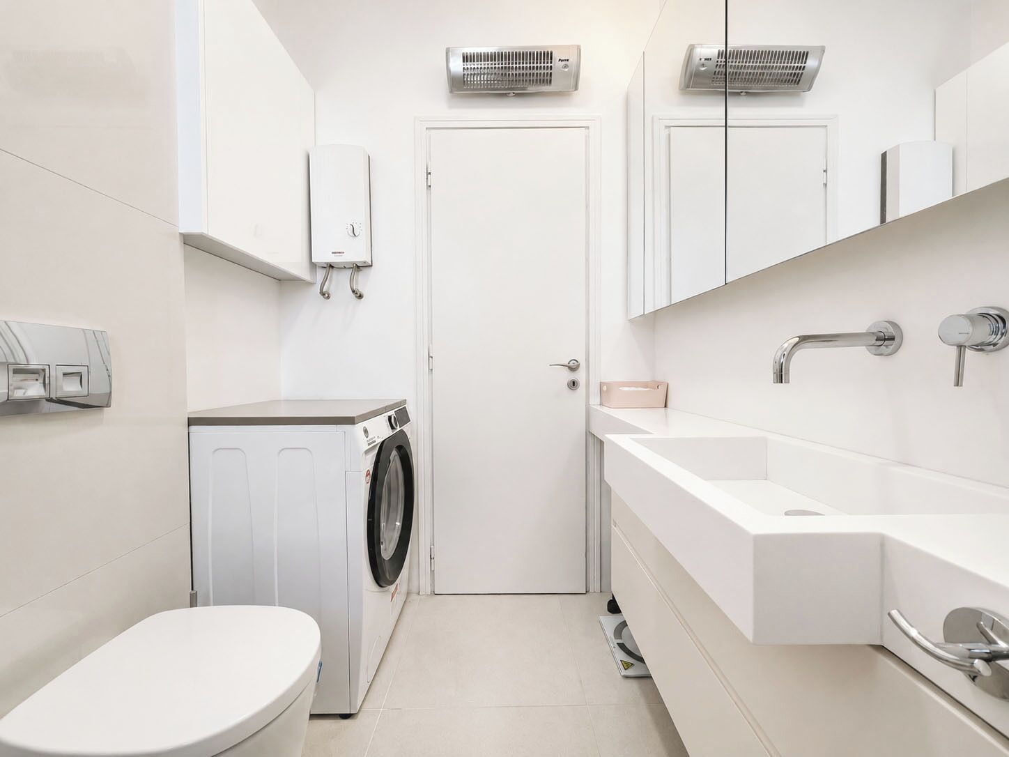 Une petite salle de bain équipée d’un lave-linge, de toilettes, d’un lavabo et d’un miroir.