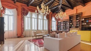 Un salón amplio con un sofá blanco grande, una estantería y una araña.
