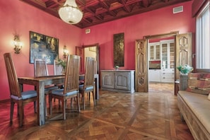 Un coin repas avec une table et des chaises en bois, un lustre et un mur rouge.