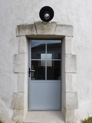 Une porte avec un panneau de verre, une poignée en métal et un objet circulaire placé au-dessus.