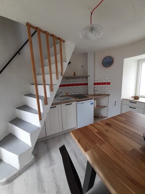 A kitchen with white cabinets, a wooden staircase, and a dining table.
