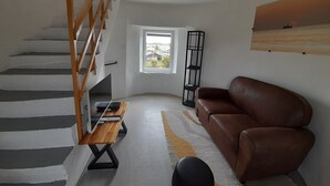 Un salon avec un escalier, un canapé en cuir marron, une table basse en bois et un lampadaire noir.