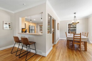 Eine Küche mit Holzausstattung, einem Edelstahlkühlschrank und einem Essbereich mit Holztisch und Stühlen.