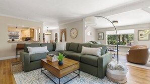 A modern living room with a sectional sofa, a coffee table, and a large window providing natural light.