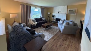 Een woonkamer met een open haard, twee banken, een salontafel en uitzicht op de omgeving.