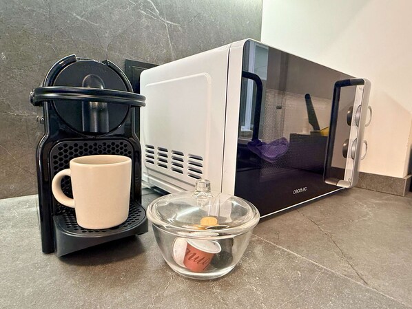 A coffee maker, a mug, and a clear glass container with a lid on a countertop.