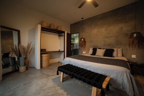 A bedroom with a bed, a bench, a ceiling fan, and a wall-mounted shelf with baskets.