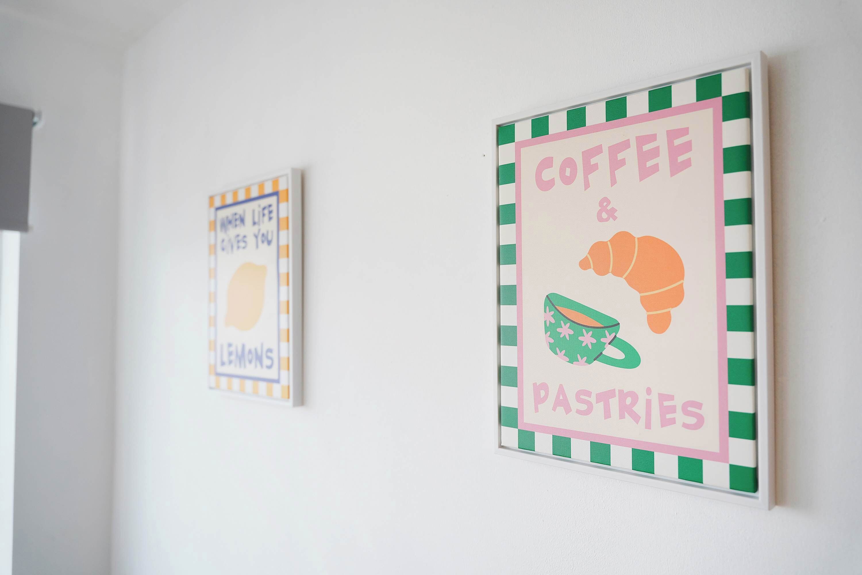 Zwei gerahmte Schilder an einer Wand, auf dem einen steht 'WHEN LIFE GIVES YOU LEMONS' und auf dem anderen 'COFFEE & PASTRIES'.