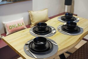 A dining table with black bowls and plates, a pillow with 'OHLALA' text, and a wooden table surface. - Bright 4BR Norton Getaway Sleeps 7 by Stay With Us (Stockton-on-Tees)