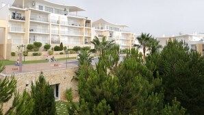 Um hotel com vários andares, varandas, piscina e um jardim ajardinado.
