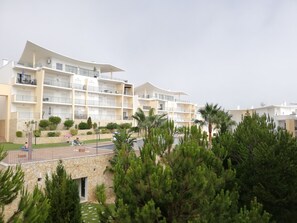 Ein mehrstöckiges Hotel mit Balkonen, einem Schwimmbad und einem angelegten Garten.