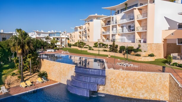 Resort com piscina, várias varandas e céu claro.