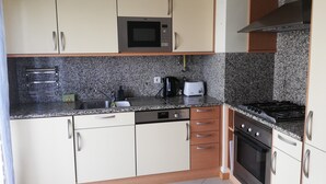Uma cozinha equipada com micro-ondas, torradeira, pia, máquina de lavar louça e fogão.