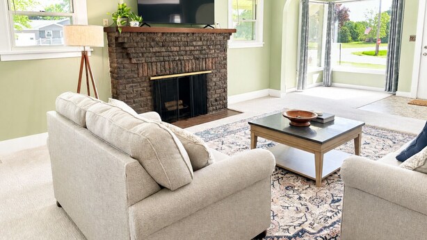 Una sala de estar con chimenea, sofá, mesa de centro y televisor.