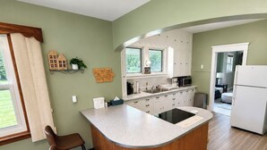 Una cocina con una isla central, un comedor con dos sillas y vistas al exterior.