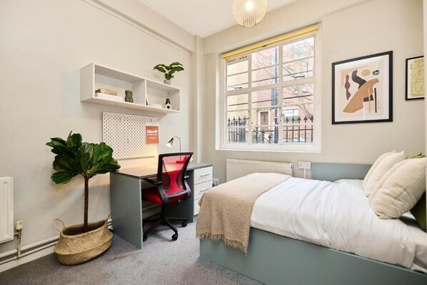 Ein Schlafzimmer mit Bett, Schreibtisch, Stuhl und einem Fenster mit Blick.