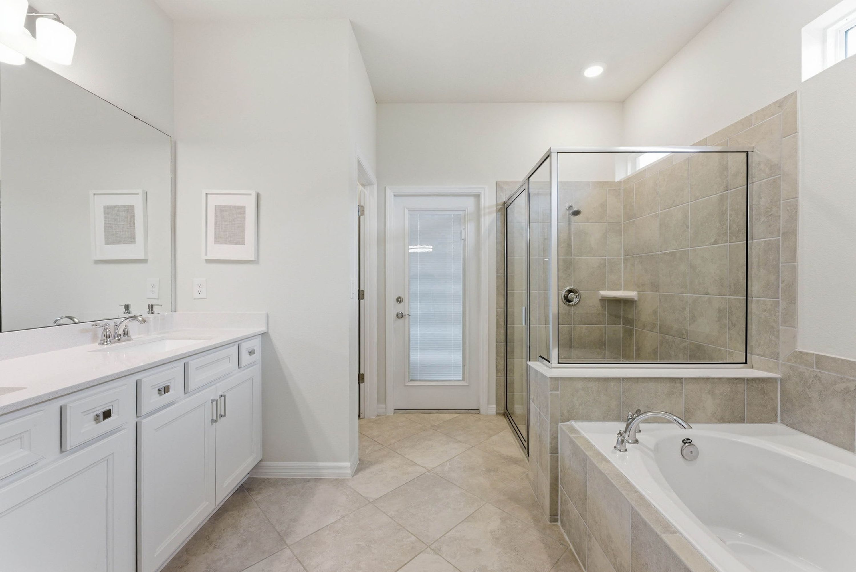 A bathroom with a glass shower enclosure, a bathtub, and a double sink vanity.