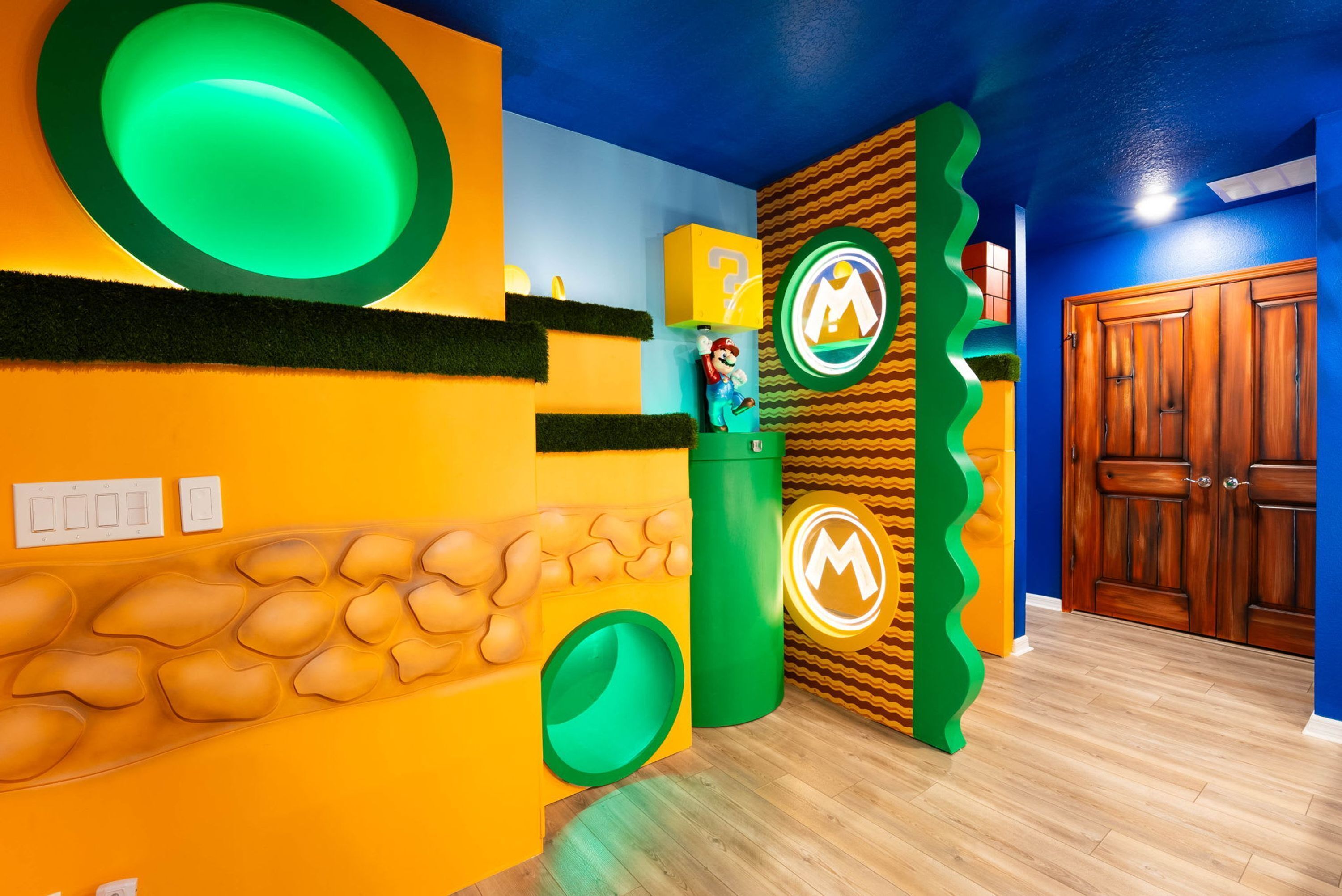 Una stanza con soffitto blu, una porta di legno e un muro decorato con un motivo verde e giallo.