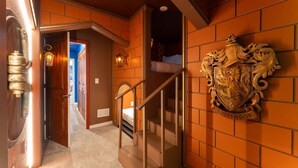 Una scala conduce a una camera da letto con uno stemma decorativo sulla parete.