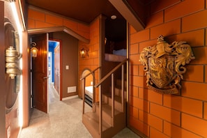 Eine Treppe führt zu einem Schlafzimmer, dessen Wand durch ein dekoratives Wappen verziert ist.