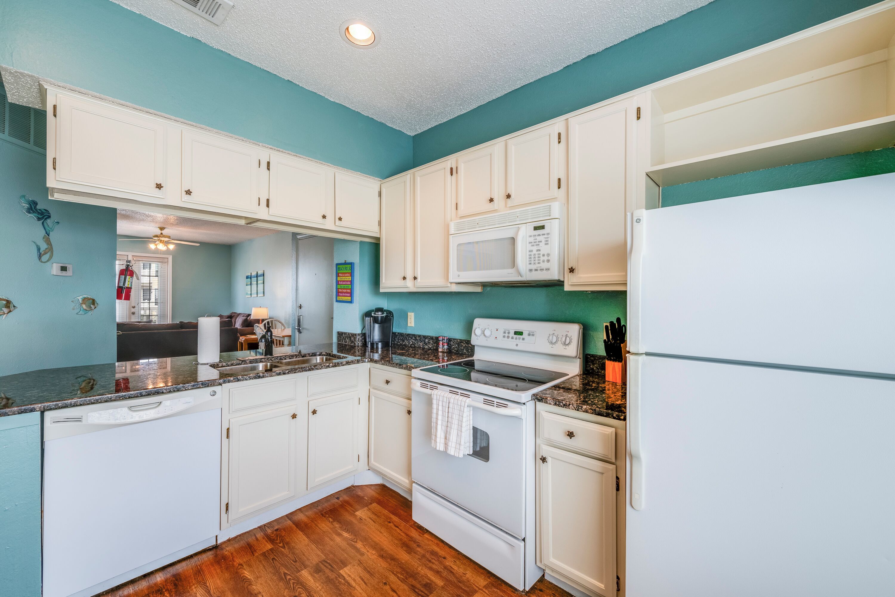 A kitchen with white cabinets, a microwave, a stove, and a refrigerator.