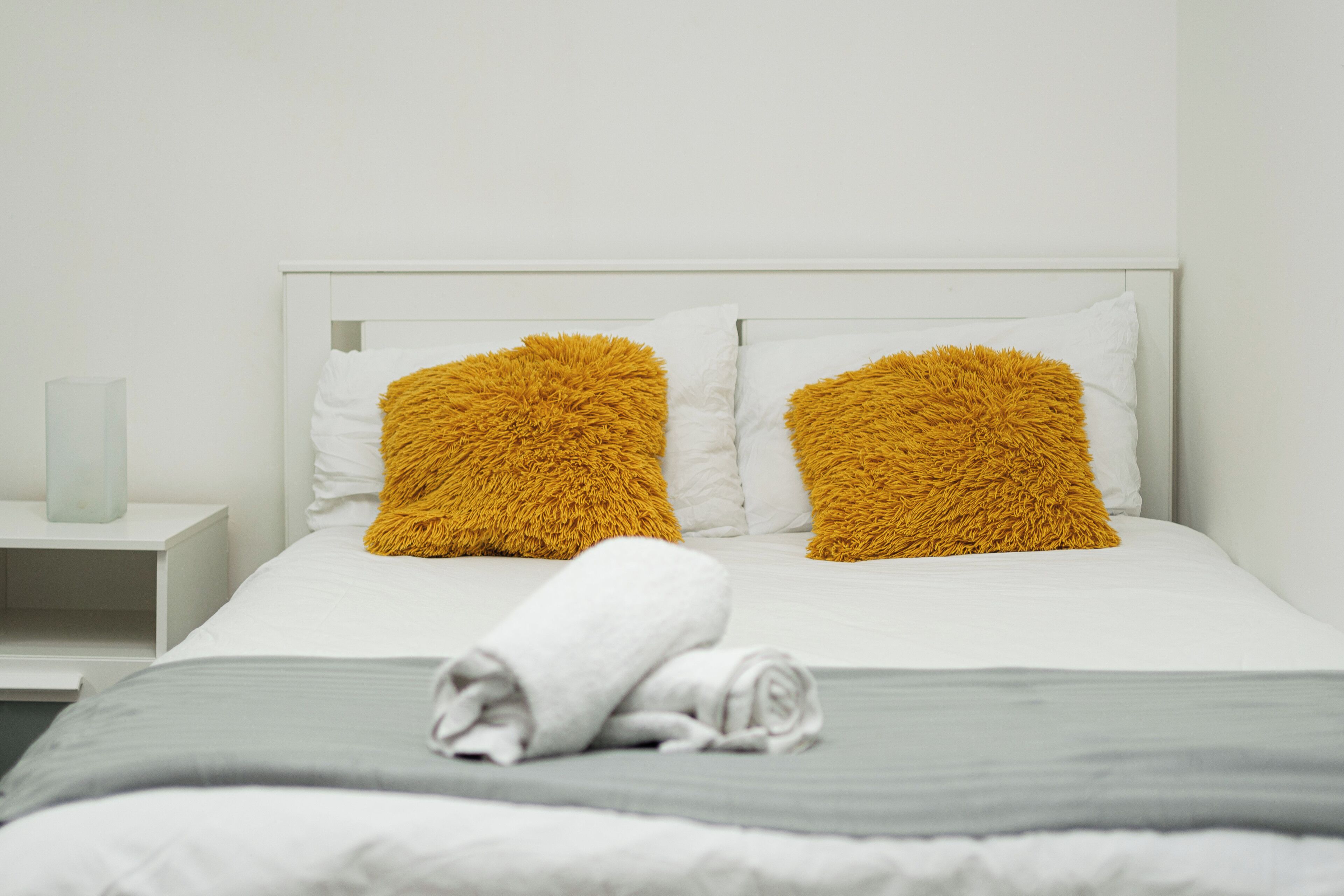 Una cama bien hecha con ropa blanca y dos almohadas grandes y mullidas.