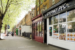 Straßenansicht mit einem Restaurant von Stepney PFC, einer roten Tür und einem Bürgersteig.
