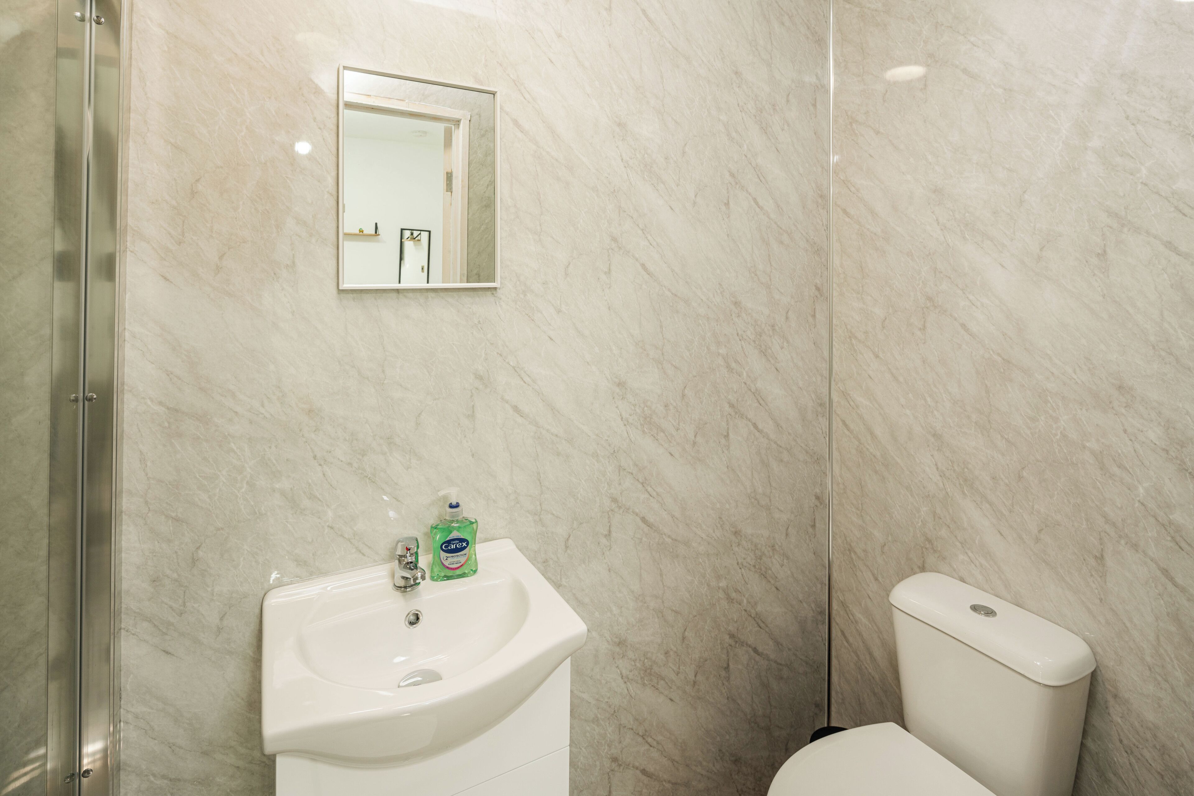 Une salle de bain avec un lavabo blanc, un miroir et des toilettes.