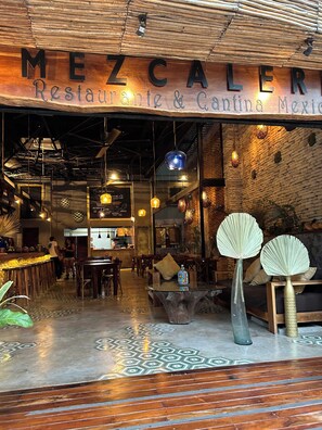A restaurant interior with a wooden ceiling, hanging lights, and a bar area. - Tulumaya Boho Luxe Villa in Aldea Zama Concierge (Tulum)